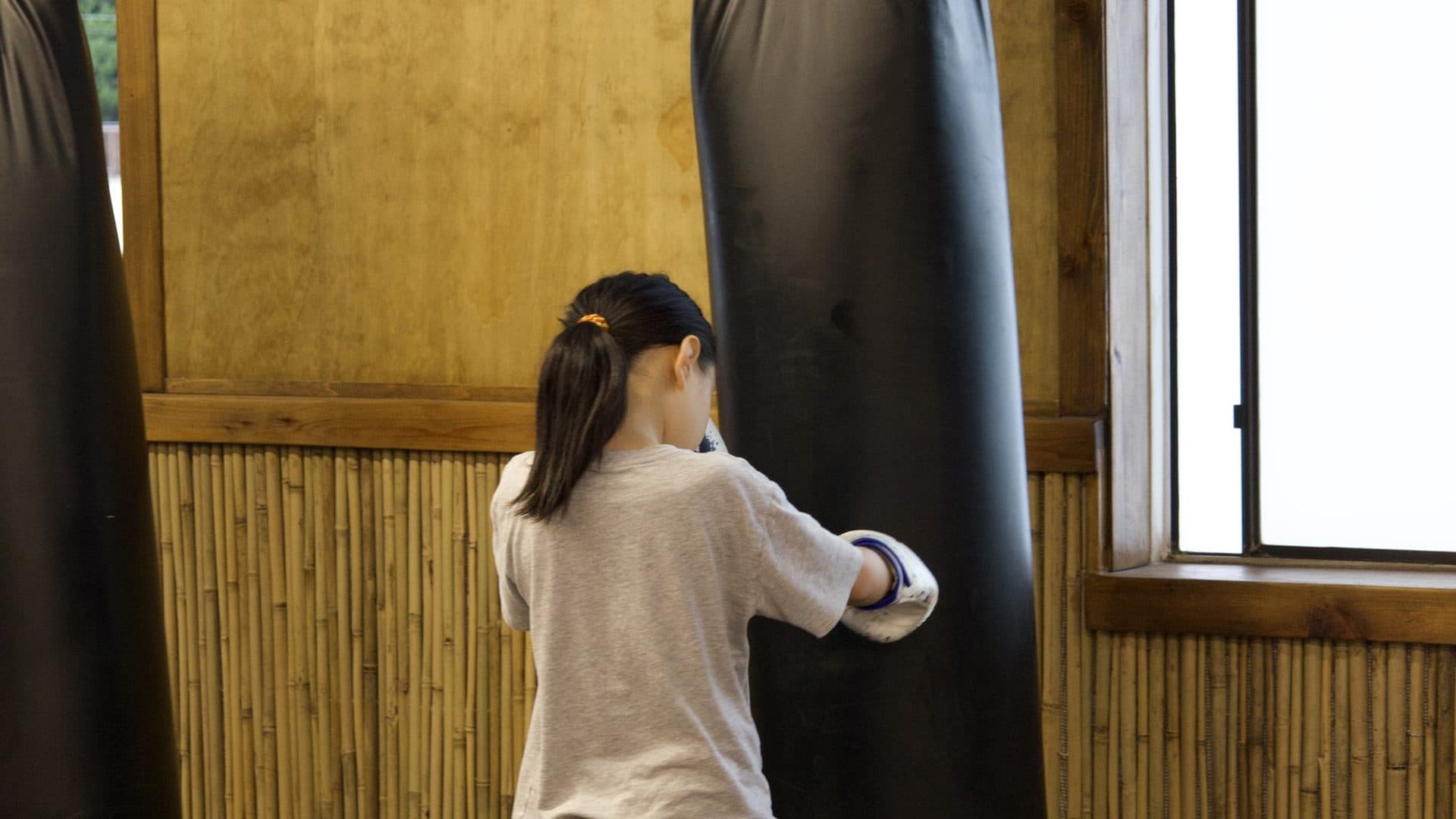 kids boxing classes white rock at Kingdom Athletics: a young boxer working the heavy bag
